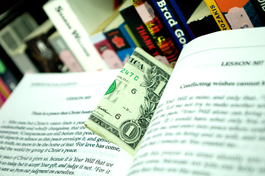 a dollar bill caught between the pages of a course in miracles book