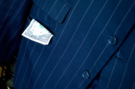a dollar bill hanging out of a men's blazer pocket