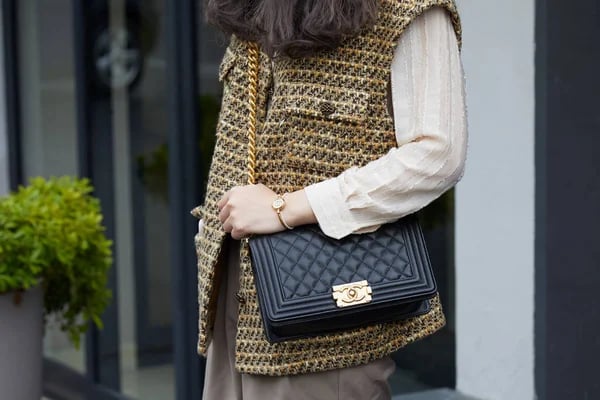 Woman with black Chanel leather bag and brown and yellow jacket before Fila fashion show, Milan Fashion Week street style — Stock Photo, Image